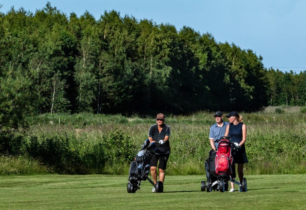Golfspillere med trolleyer på banen