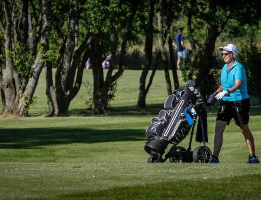 Golfspiller på banen med trolley